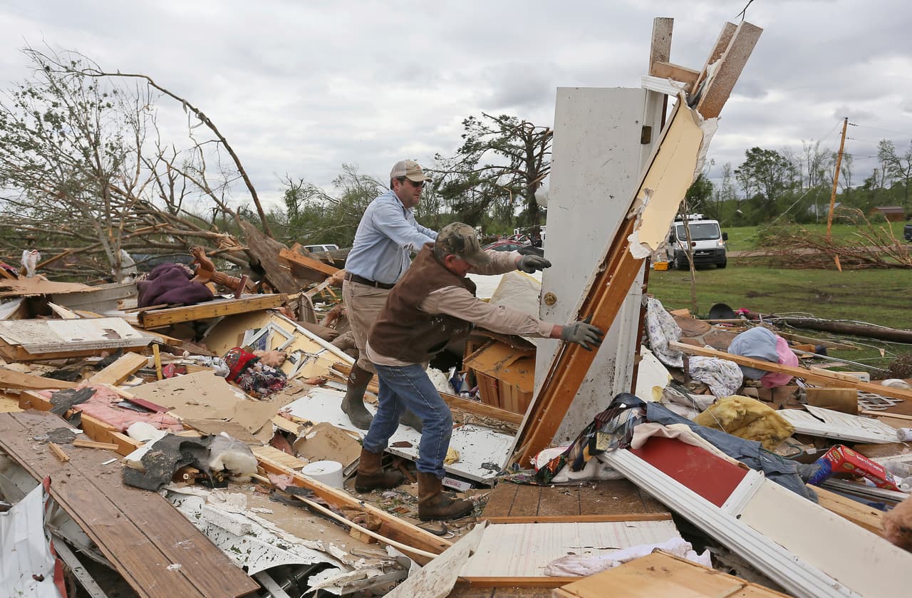 Roman Brown y Sam Crawford mueven parte de un muro mientras ayudan a un amigo a buscar su medicamento en su casa destruida a lo largo de Seely Drive, en Mississippi.