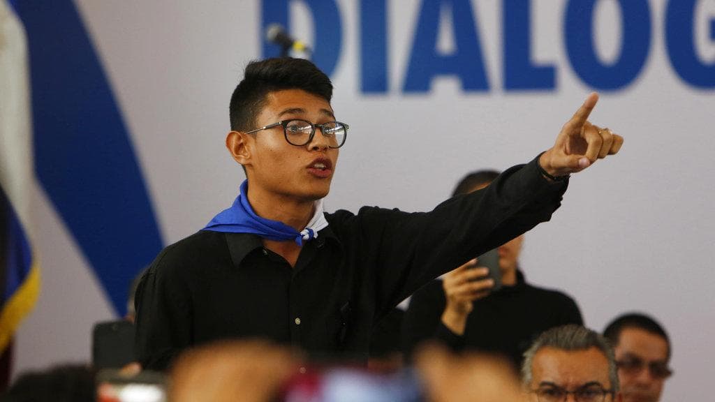 Student representative, Lester Alemán, wearing a bandana in the blue and white national colors interrupts President Daniel Ortega and demands that the police repression of the protests cease.