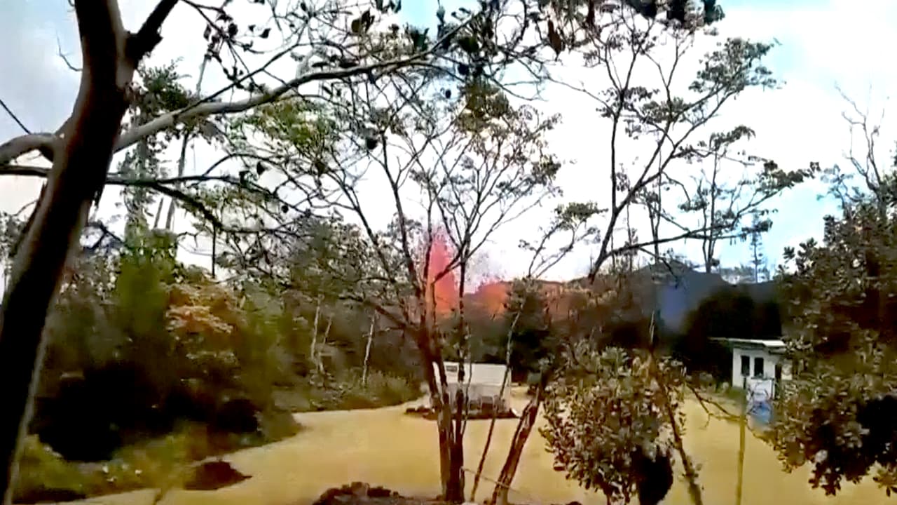 Un chorro de lava sale de una de las fisuras, justo al lado de una casa en Leilani Estates.