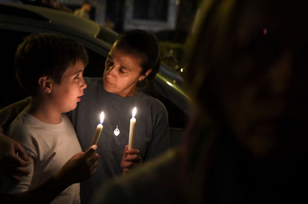 Una mujer y un niño sostienen velas durante una vigilia organizada el miércoles en la noche, frente a la escuela secundaria Politécnico donde cinco argentinos murieron en el ataque del martes.