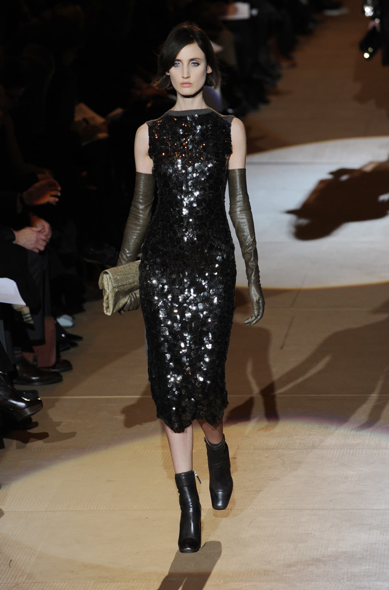 El traje de corte recto, de falda tipo lápiz con lentejuelas en el frente y guantes verdes como accesorios fue creado por 
<b>Marc Jacobs</b> para el 
<b>Fall 2010</b>