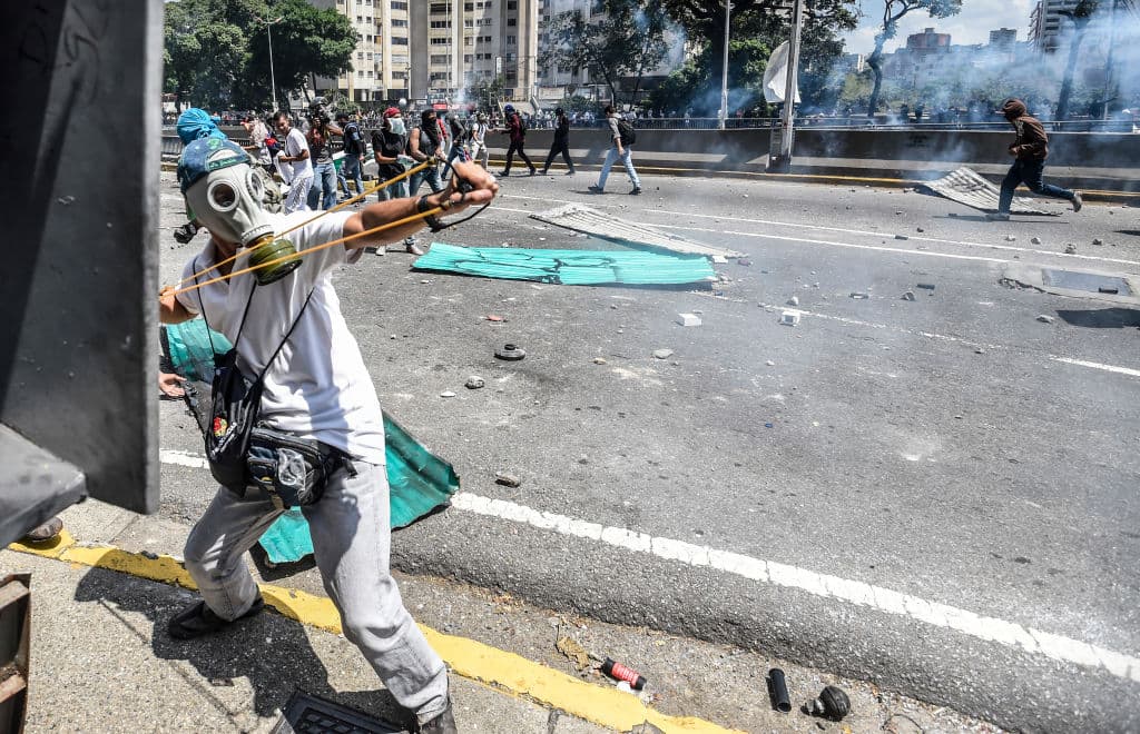 Un manifestante usa una resortera para atacar a la policía en una calle en Caracas, Venezuela.