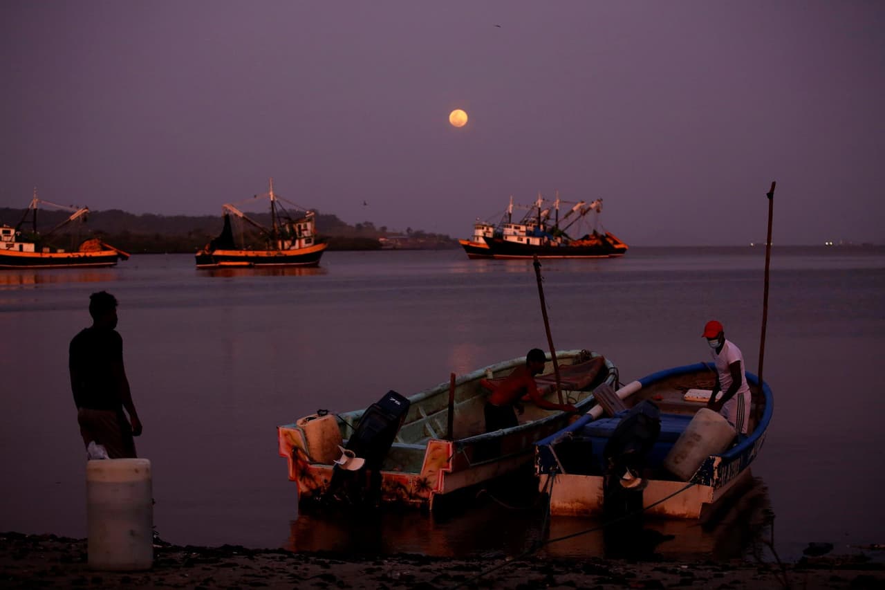 Pescadores recogen sus redes bajo la superluna rosa que se eleva en el cielo en el pueblo pesquero de Puerto Caimito, Panamá.
