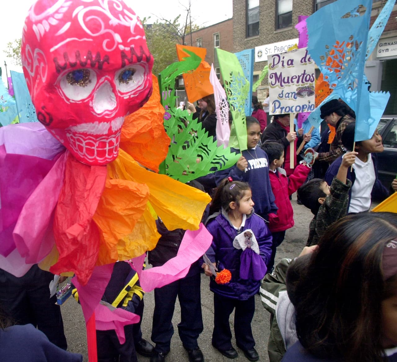 Niños de una escuela de primaria, padres y personas de la comunidad, comienzan una procesión en el vecindario Pilsen / La Villita de Chicago celebrando la tradición del Día de los Muertos. Algunos de los participantes llevaron Mojigangas. Hecho de papel maché, que se utilizan en procesión en México.