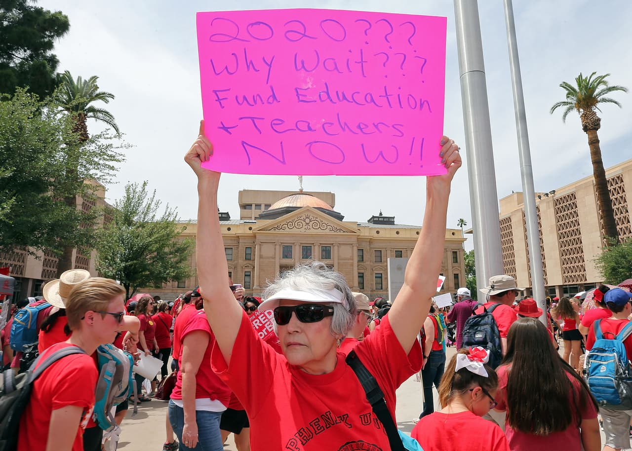 A sus 73 años Ester Lumm sostiene un letrero frente al Capitolio estatal durante una manifestación en apoyo de los maestros de Arizona en apoyo a la lucha de los maestros por mejores salarios y mayor presupuesto para las escuelas públicas.