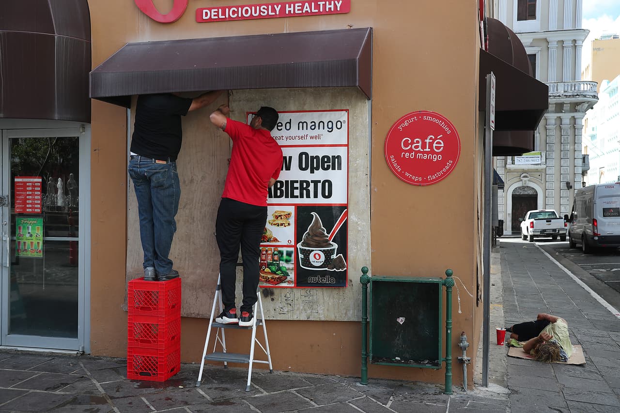 José Rodríguez e Ian Rodríguez colocan madera contrachapada sobre las ventanas de su negocio mientras intentan protegerlo contra la posible violencia durante la manifestación programada para hoy.