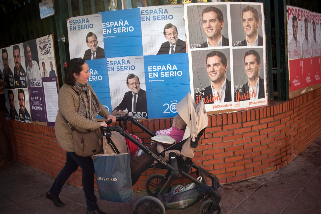 Una mujer pasea delante de una pared con carteles electorales.