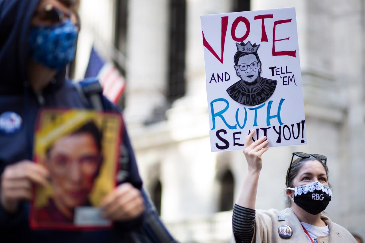 Esta manifestante, sostiene una pancarta con la imagen de Ruth Bader Ginsburg que dice "Vota y diles que Ruth te mandó".