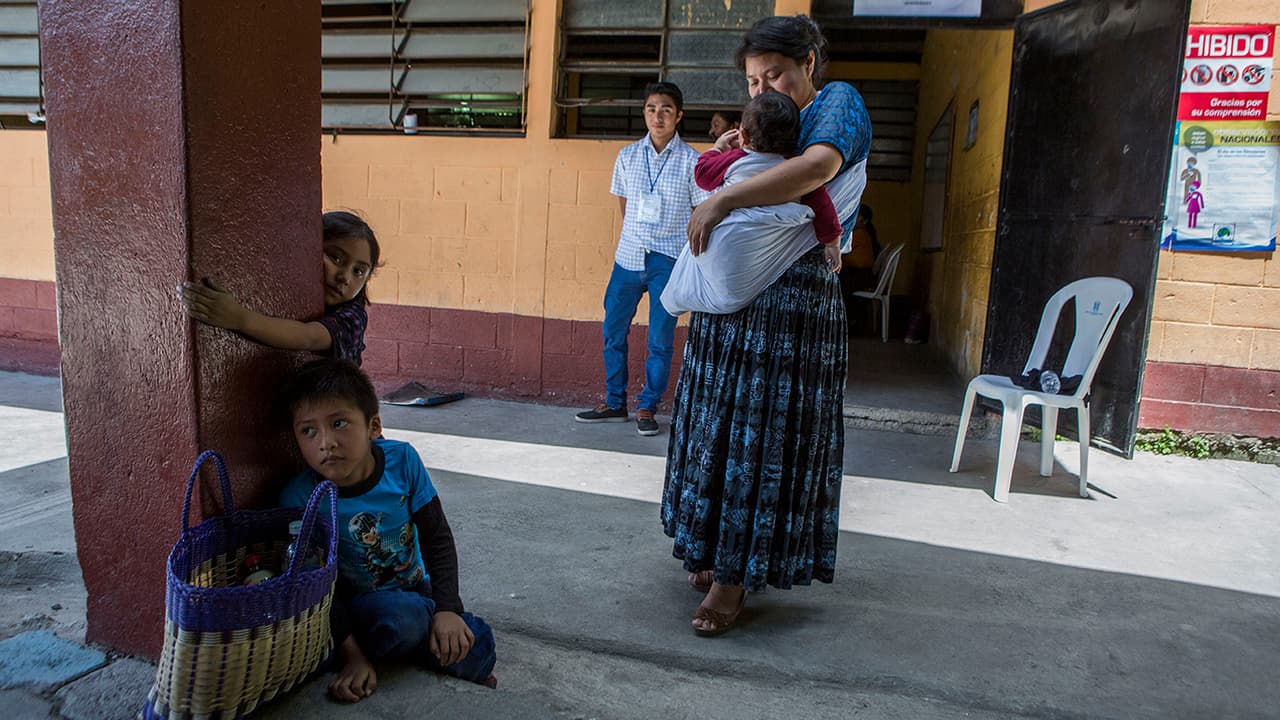 Una mujer y sus hijos esperan afuera de un sitio designado para votar, en Chinautla, afuera de la ciudad de Guatemala.