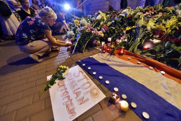 Personas dejan ramos de flores en conmemoración de las víctimas del avión estrellado de Malaysia Airlines al este de Ucrania frente de la embajada de Holanda en Kiev.