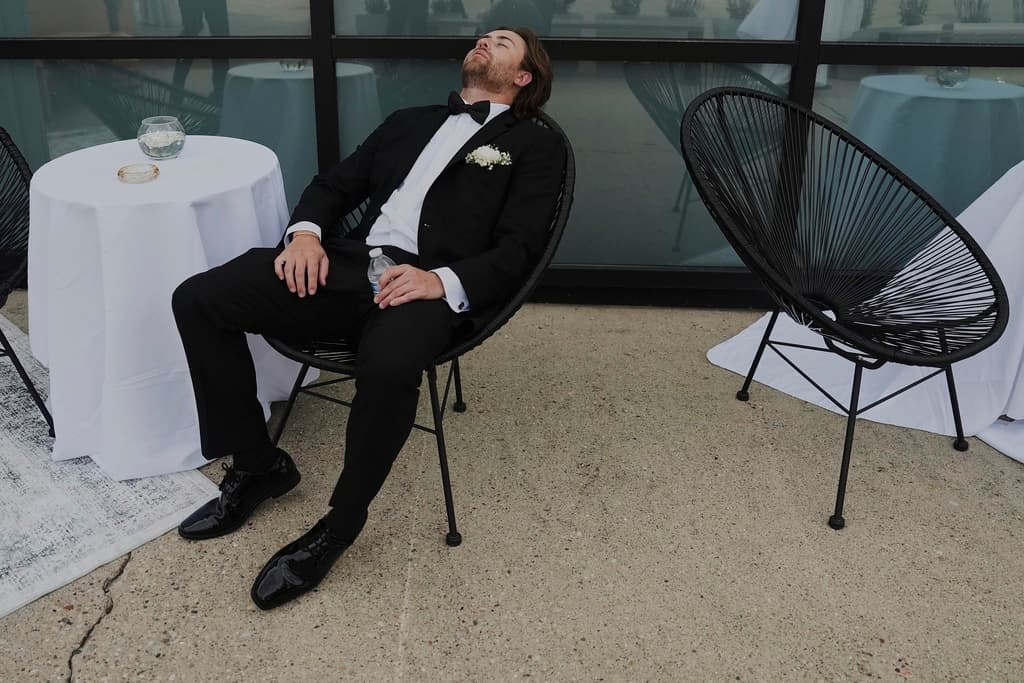 El padrino de boda, Ethan Morton, se toma un descanso tras terminar las fotos de la fiesta nupcial en una boda el sábado 23 de agosto de 2025 en Newtown, Ohio. (Foto AP/Joshua A. Bickel)