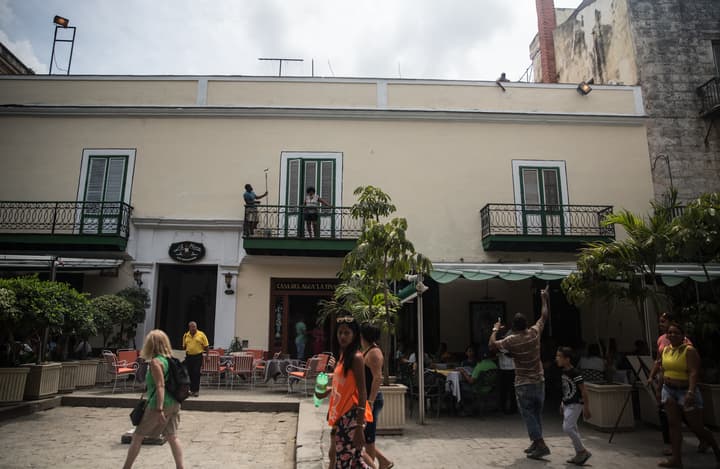 Hombres retocan la fachada de un inmueble en la calle Obispo, el principal bulevar del centro histórico de La Habana.
