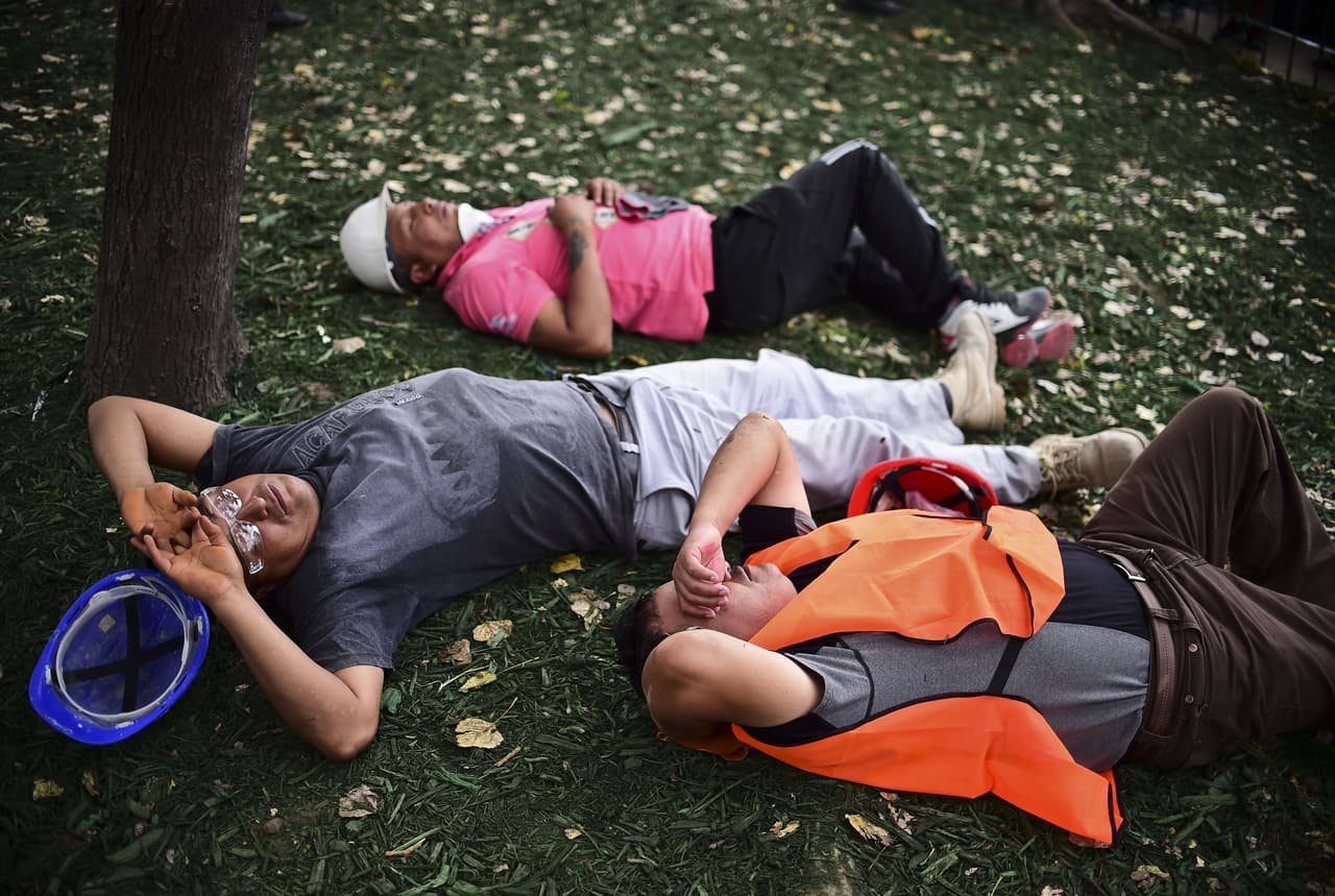 Voluntarios toman un descanso, luego de casi dos días de trabajo continuo en la búsqueda de sobrevivientes.