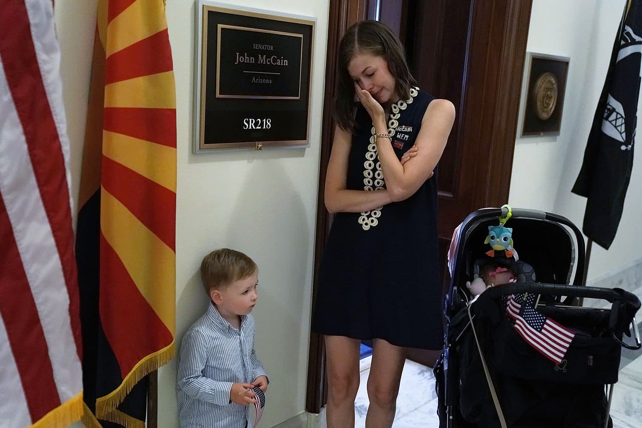 Varios se han acercado al despacho de McCain en el edificio del capitolio de EEUU en Washington DC. Ashley Harper, exmiembro del equipo de campaña del senador, llora frente a la oficina junto a su hijo.