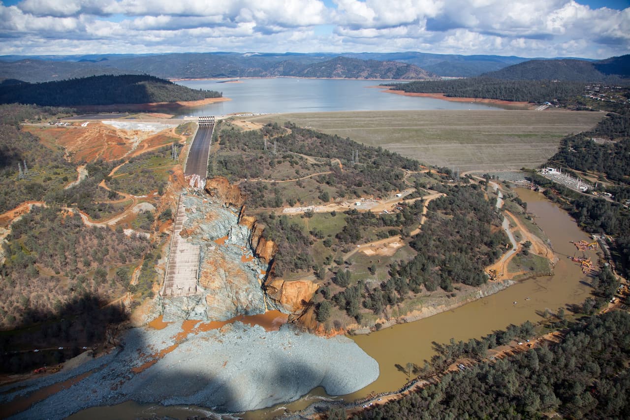 En esta imagen se observa cómo la mitad de la rampa está destrozada y la gran escombrera de roca y desechos que se han acumulado en el lecho del río Feather, que se alimenta del agua de la represa.