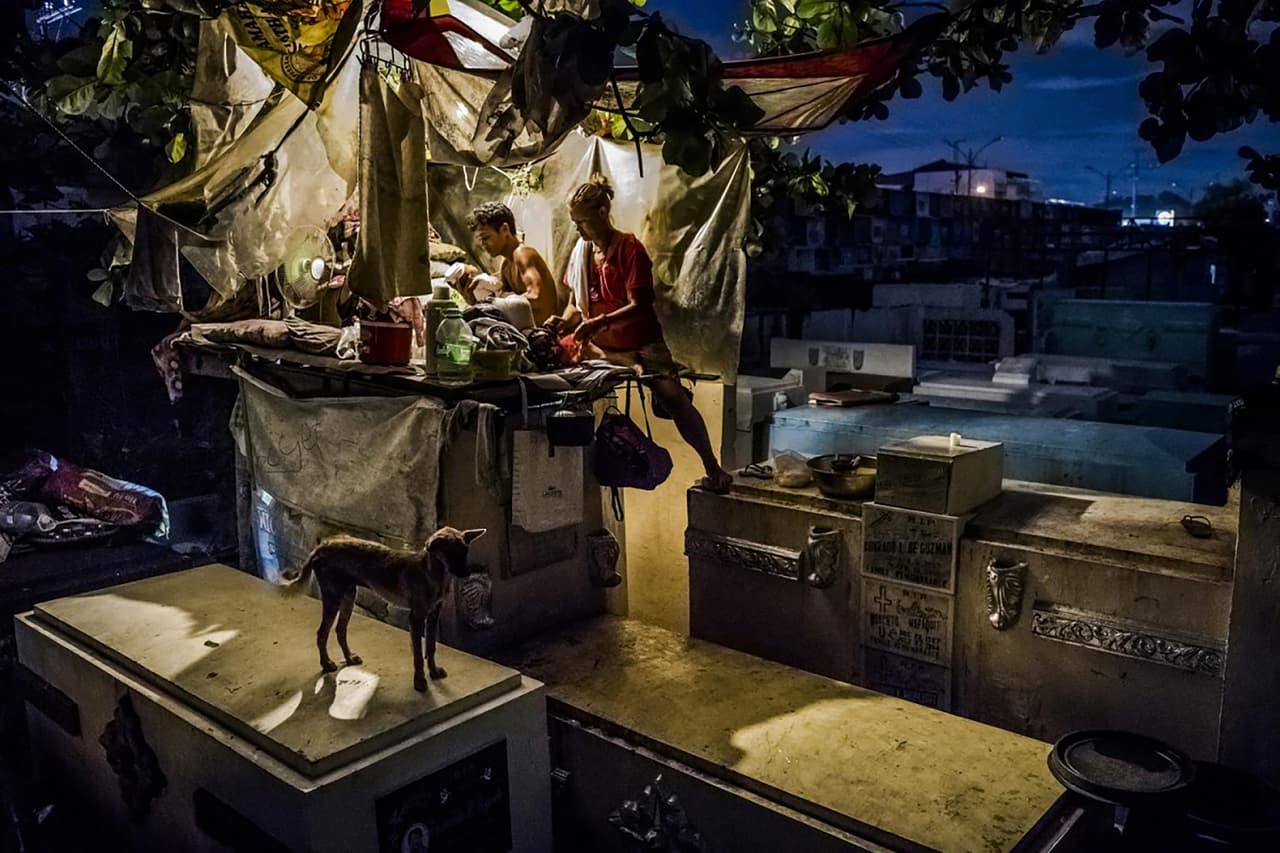 <b>La guerra contra el narcotráfico en Filipinas.</b> Con tantos asesinatos, los cementerios se han convertido en lugares macabros de reunión. En el Cementerio Norte de Manila, un hombre que vive con su familia en una tienda erigida encima de una lápida. En la fotografía alimentando a sus gemelos de 2 meses de edad.