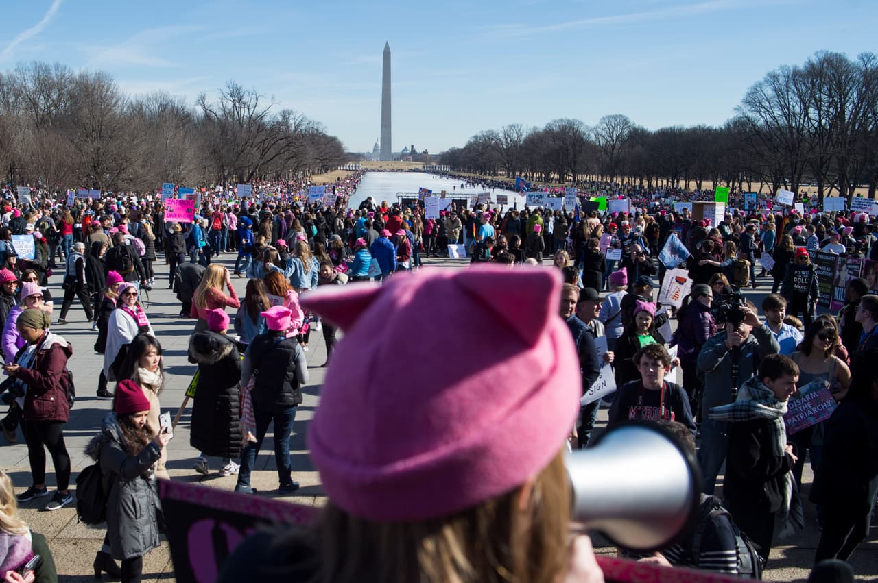 En primer plano, una mujer con un pussyhat encara a la multitud en Washington, DC.