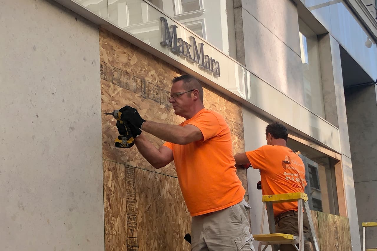 Pero los dueños de negocios prefieren prevenir que lamentar. En la imagen, dos trabajadores colocan tablones de madera sobre los ventanales de la tienda Max Mara, en la zona de Union Square de San Francisco.