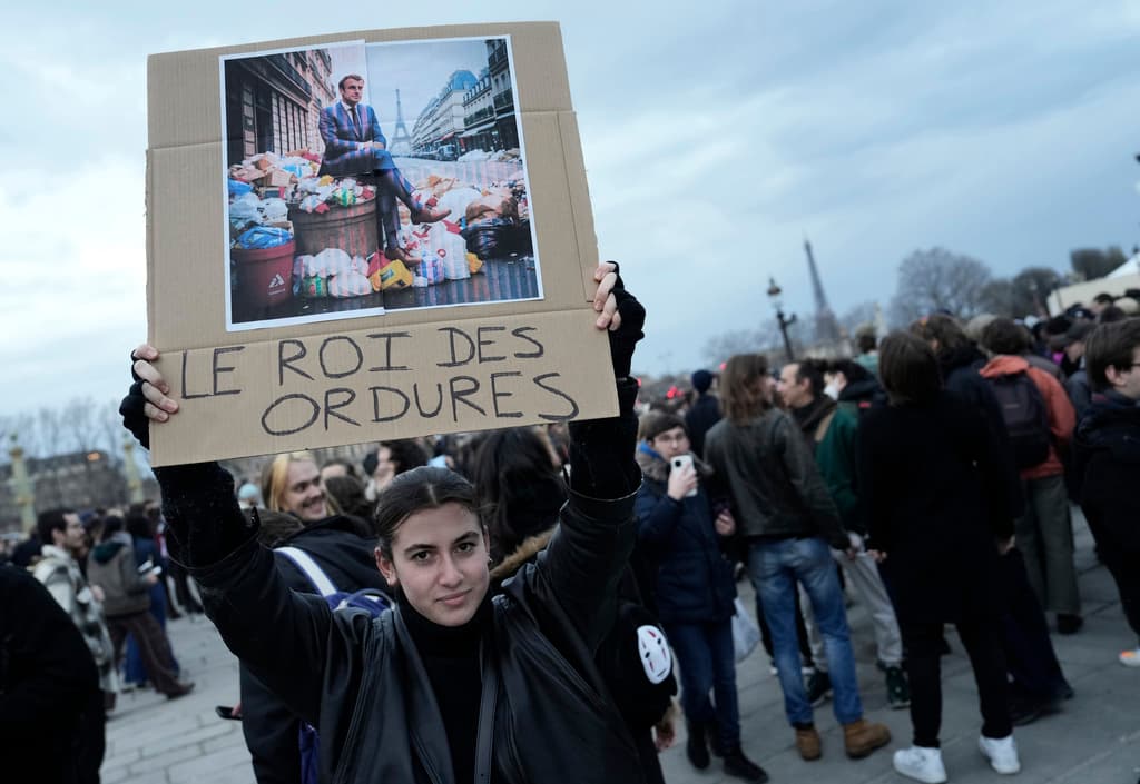 Una mujer sostiene un cartel con una imagen del presidente de Francia, Emmanuel Macron, sentado sobre una pila de basura con la franse "rey de la basura", durante una protesta en París este viernes.