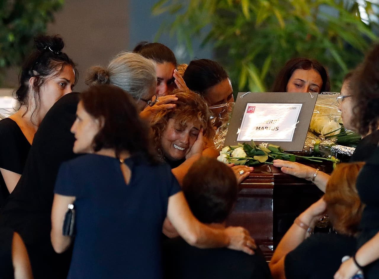 A woman is comforted as she mourns a victim of a collapsed highway bridge, at the Fiera di Genova exhibition center, where some of the victims are laid in state, in Genoa, Italy, Friday, Aug. 17, 2018. A state funeral for most of the victims will take place in Genoa on Saturday. (AP Photo/Antonio Calanni)