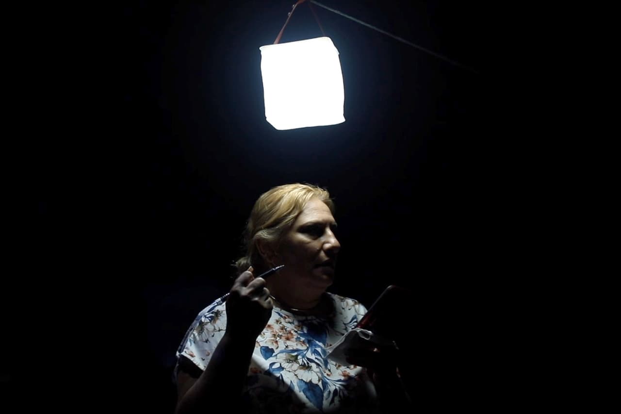 Wanda Villafañe mientras habla con un representante de FEMA y una traductora en medio de la oscuridad en Puerto Rico.