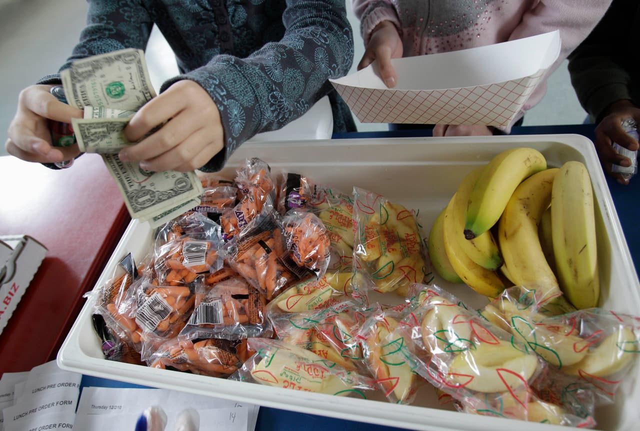 FILE - In this Dec. 2, 2010, file photo, a student at Fairmeadow Elementary School pays for lunch consisting of fruits and vegetables during a school lunch program in Palo Alto, Calif. California is home to the nation's largest agricultural economy, but the state auditor says it does little to ensure schools follow federal rules requiring they serve food produced in the United States. The audit released Thursday, July 27, 2017, says the California Department of Education only recently began checking where school food is produced, and it says the reviews are too weak. (AP Photo/Paul Sakuma, File )