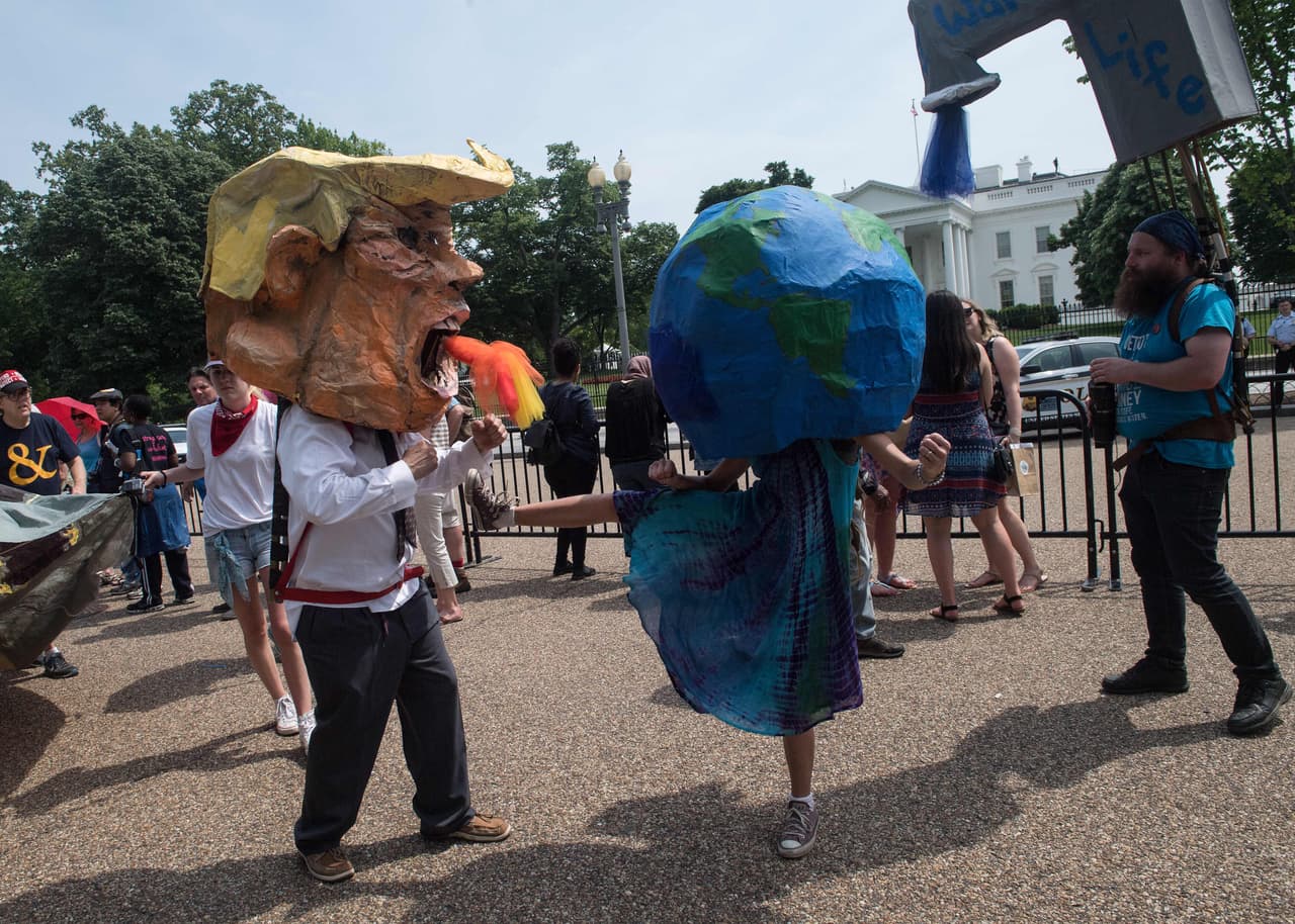 Manifestantes en máscaras del presidente Trump y la Tierra simulan pelear como simbolismo de la protesta.