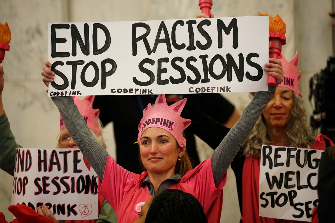 Una mujer con una pancarta que lee "pongan fin al racismo, frenen a Sessions". Durante la audiencia, el congresista negó ser un racista que simpatiza con el grupo supremacista blanco Ku Klux Klan. (Foto de Kevin Lamarque/Reuters)