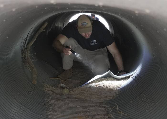 Un agente del FBI registra una alcantarilla cerca de la casa de Annie Guthrie.