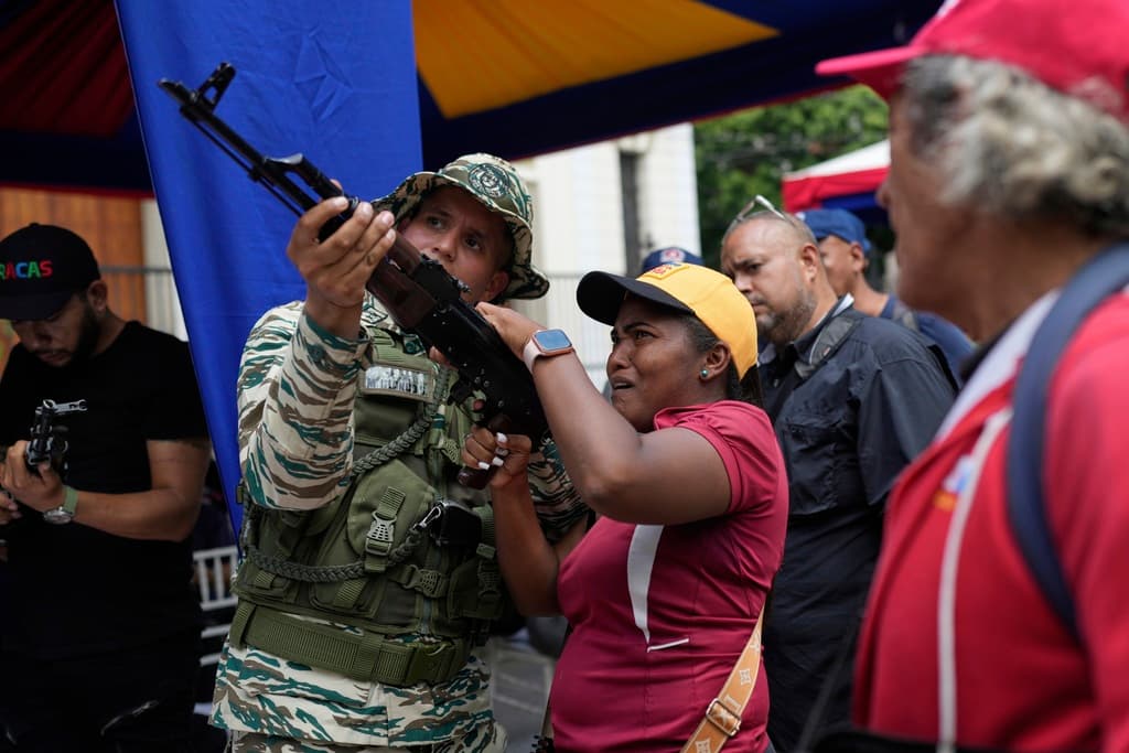 Un miembro de la Milicia Nacional Bolivariana muestra a una mujer cómo manejar un arma durante unos ejercicios militares en Caracas, Venezuela, el sábado 20 de septiembre de 2025.