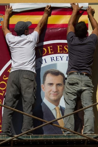 Trabajadores fijan una fotografía del Prínicipe Feipe en la fachada de una tienda de recuerdos cerca del Palacio Real.
