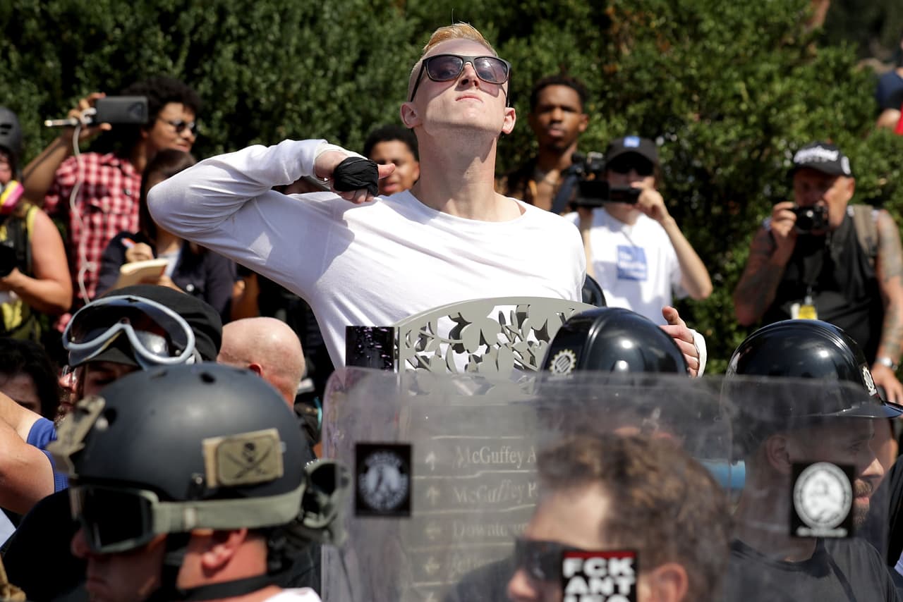 CHARLOTTESVILLE, VA - AUGUST 12: A man makes a slashing motion across his throat twoard counter-protesters as he marches with other white nationalists, neo-Nazis and members of the "alt-right" during the "Unite the Right" rally August 12, 2017 in Charlottesville, Virginia. After clashes with anti-fascist protesters and police the rally was declared an unlawful gathering and people were forced out of Emancipation Park, where a statue of Confederate General Robert E. Lee is slated to be removed. (Photo by Chip Somodevilla/Getty Images)