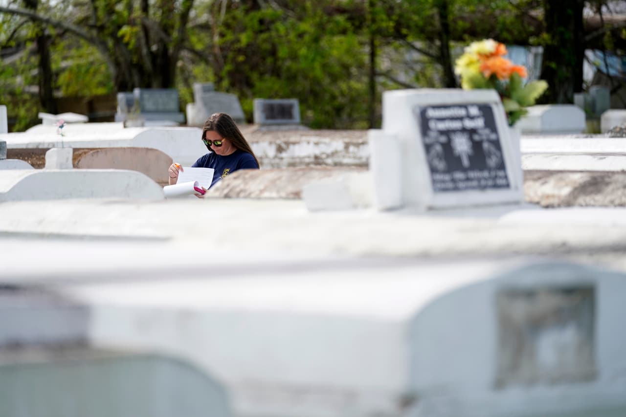 Christine Halling examina una de las tumbas afectadas. La identificación de los restos desenterrados por las
<a href="https://www.univision.com/temas/tormentas-tropicales">tormentas</a> es complicada y en ocasiones deben usarse registros dentales o pruebas de ADN.
