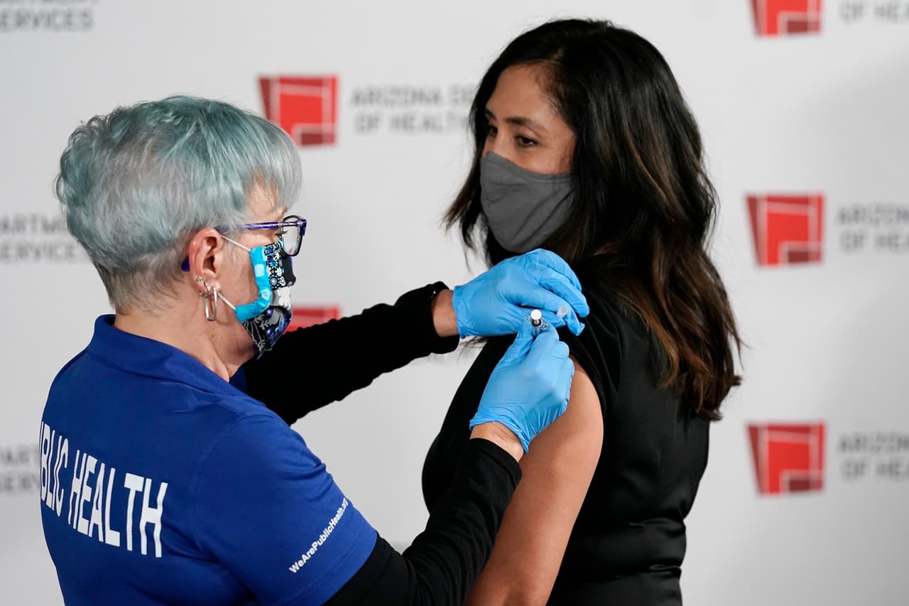 Regina Villa, jefe de enfermería de la UCI de Valleywise Health, recibe una de las primeras dosis de la vacuna Pfizer-BioNTech contra covid-19 en el Laboratorio Estatal del Departamento de Servicios de Salud de Arizona. La cifra de muertos en Arizona por el brote de coronavirus superó las 8,000 y este miércoles se reportaron 6,058 nuevos casos.