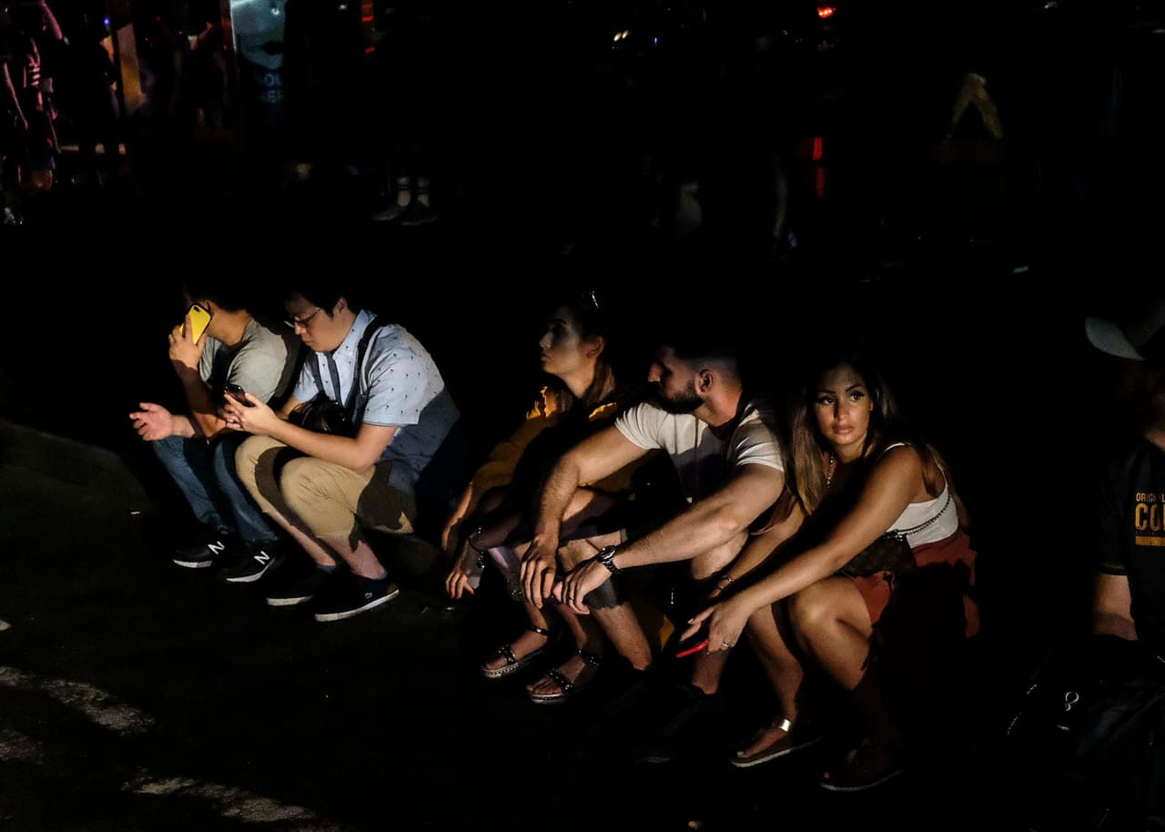 NUEVA YORK, NY - 13 DE JULIO: La gente se sienta afuera del hotel Row NYC durante el apagón. (Foto de Byron Smith/Getty Images)