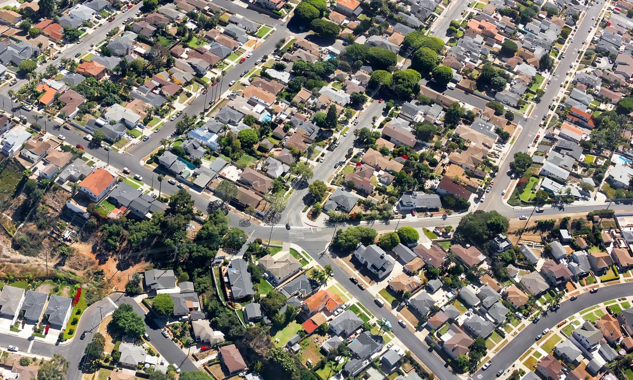 Multiple houses are seen from an aerial viewpoint over a residential neighborhood in southern California.