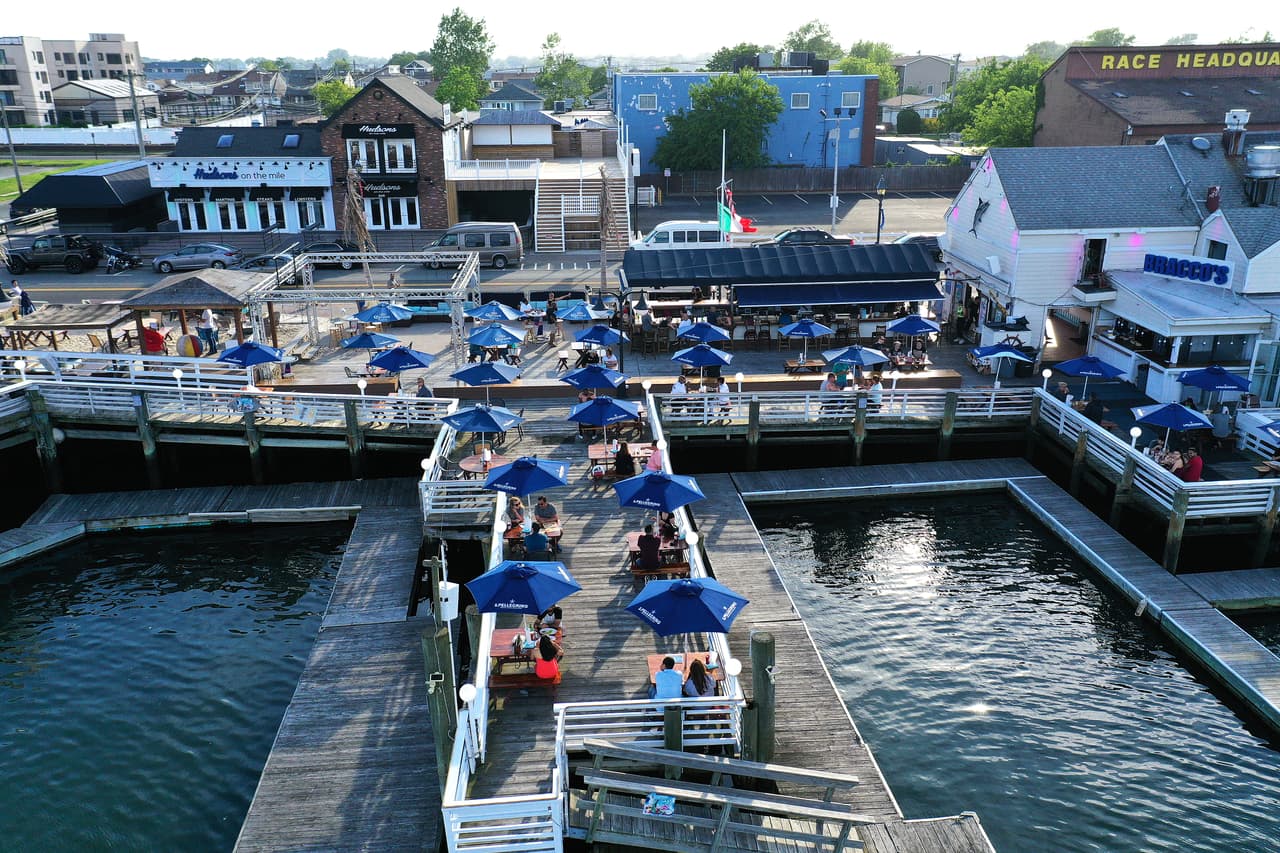 Gente comiendo en el restaurante Bracco's en Nautical Mille en Freeport, Nueva York. Las mesas están separadas por seis pies de distancia.