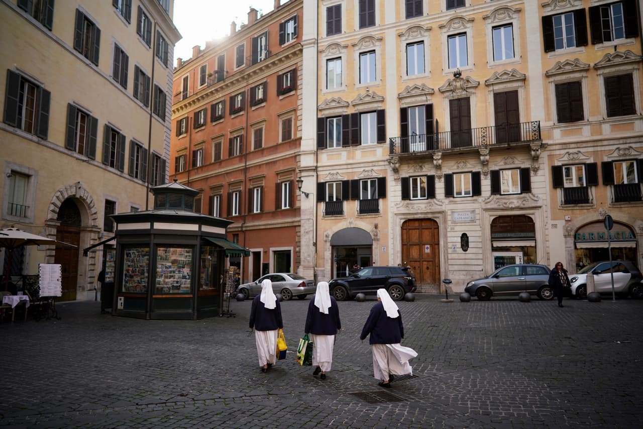 Tres monjas cruzan una plaza vacía, en Roma, este martes. Este martes el papa Francisco se vio en video celebrando solo la misa diaria en la capilla de su residencia Santa Marta en el Vaticano.
<br>