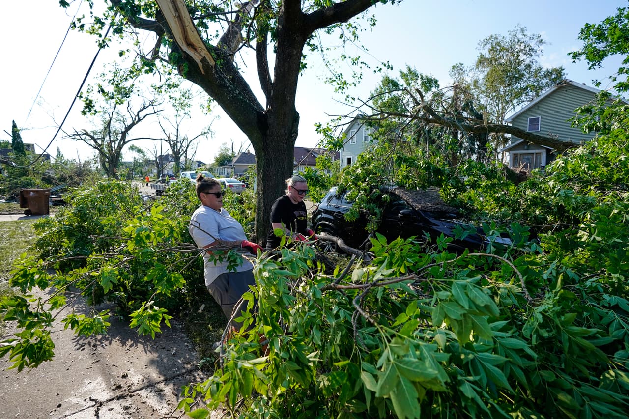 Cassandra Baron (izquierda) y Brooke Baron retiran ramas de árbol caídas de un automóvil después de que un tornado azotara la zona el lunes 27 de julio de 2026 en Menasha, Wisconsin.