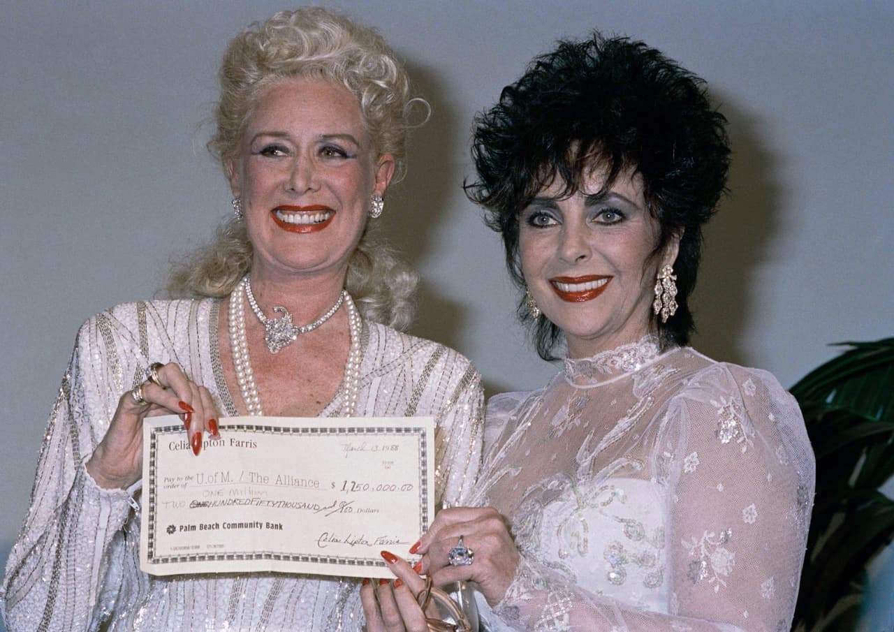 <b>Elizabeth Taylor y la cantante Celia Lipton Farris</b> muestran un cheque durante una actividad a beneficios de pacientes con VIH-Sida. 14 de marzo de 1988.