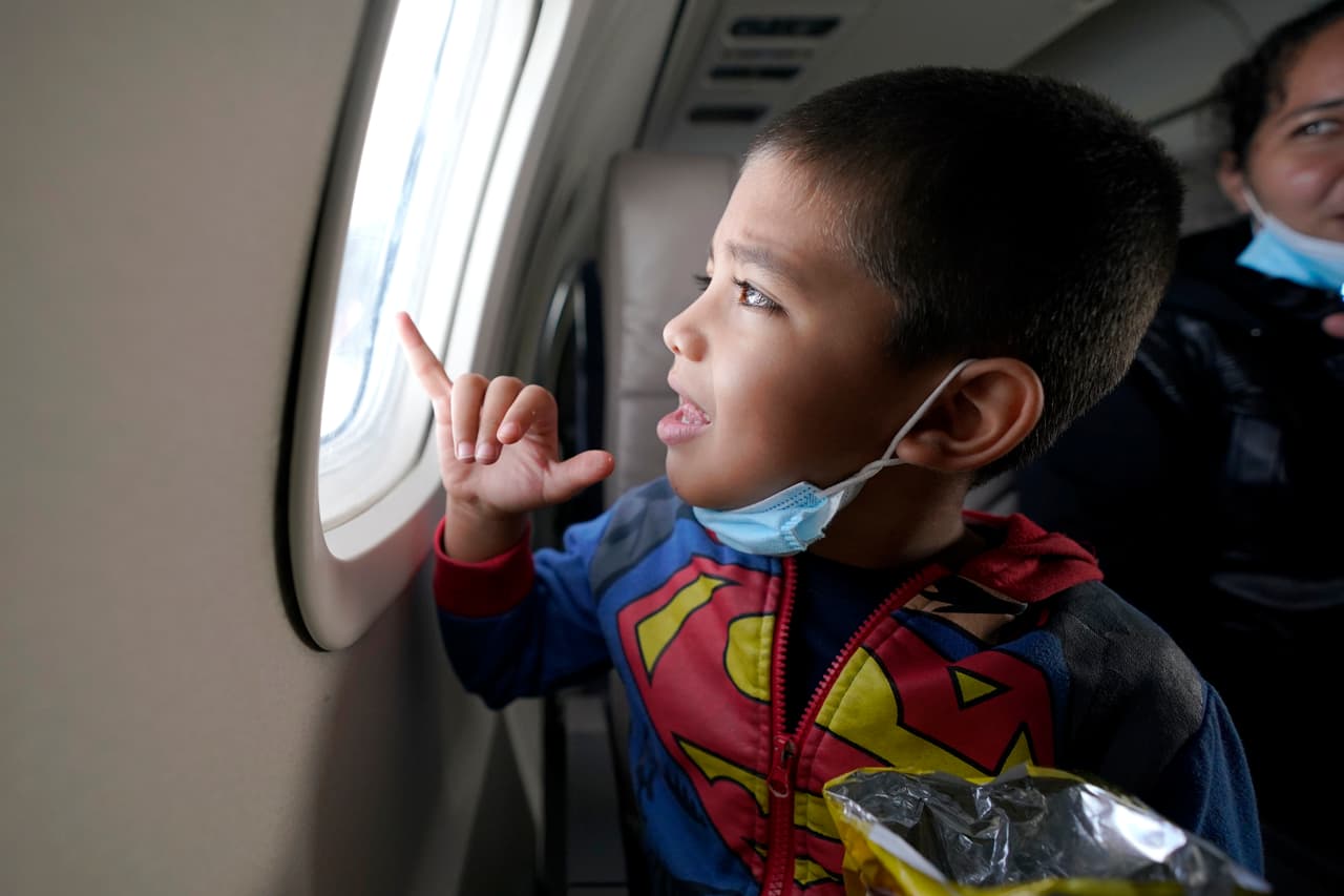 Vestido con su sudadera de Superman, Yancarlos mira por la ventanilla de un avión.
