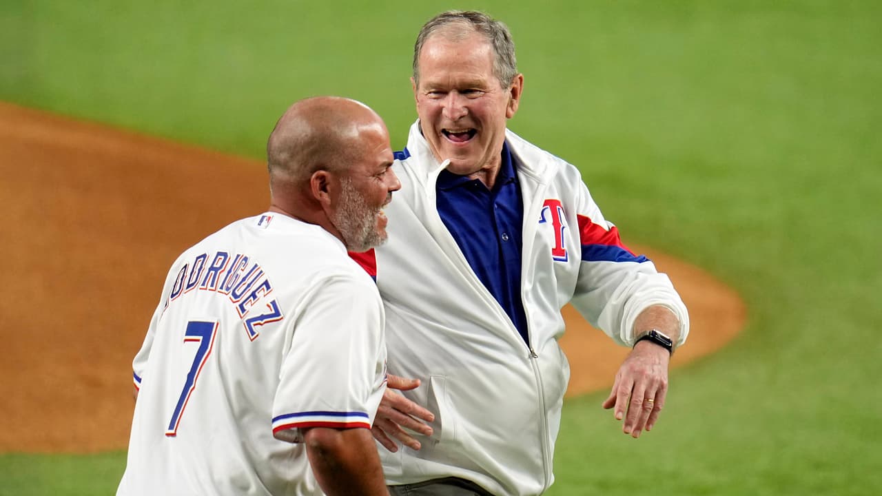 El expresidente estadounidense George W. Bush ríe junto al exjugador de béisbol puertorriqueño Iván Rodríguez, después de realizar el primer lanzamiento de la Serie Mundial el viernes 27 de octubre de 2023 en Arlington, Texas.