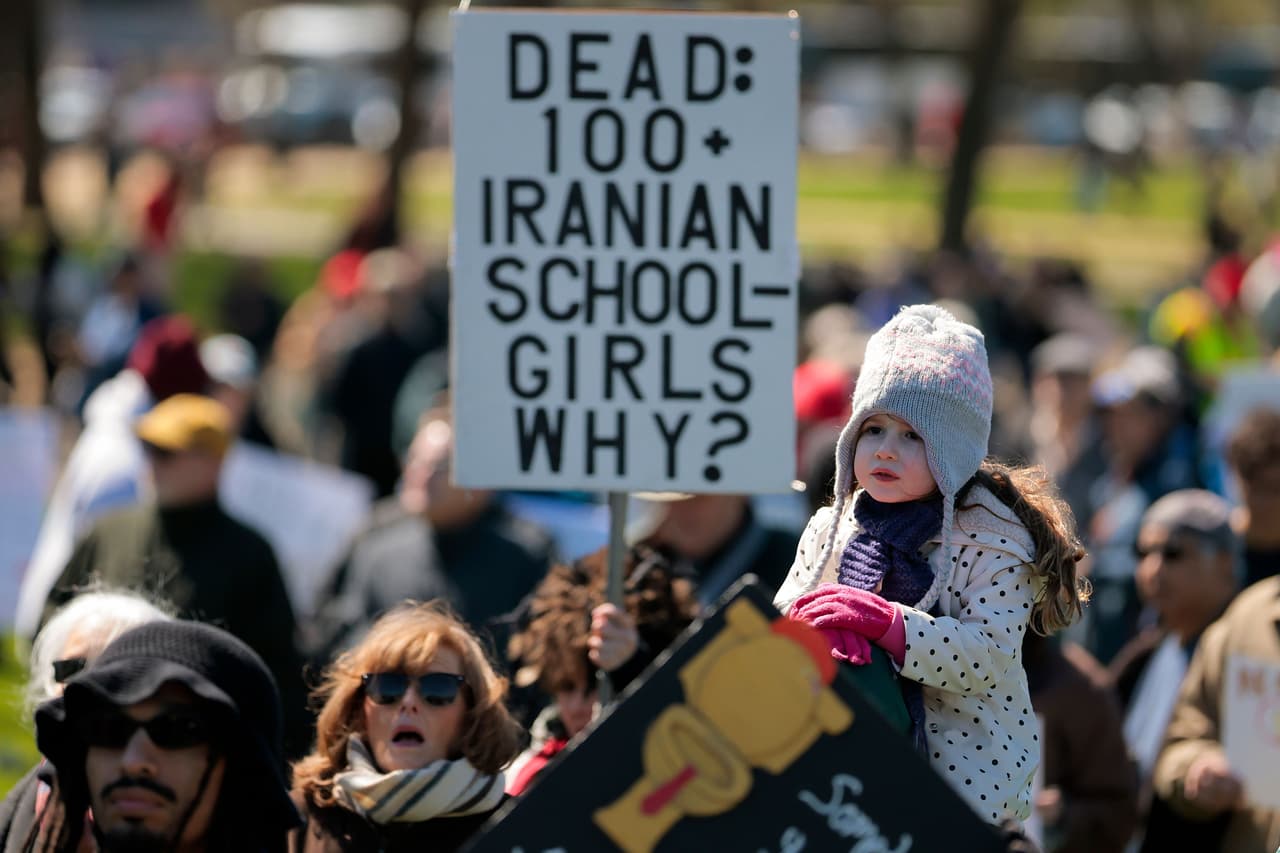 Una niña se une a la protesta No Kings, sosteniendo el letrero "Más de 100 niñas estudiantes iraníes fallecidas. ¿Por qué?", en referencia a los informes de víctimas entre escolares tras bombardeos registrados en Irán en medio del conflicto regional