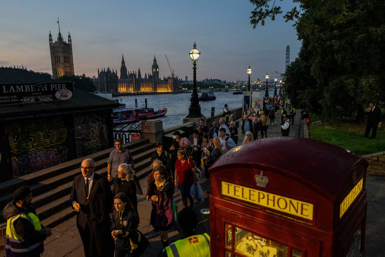 Personas esperan en fila para rendir sus últimos respetos a la reina Isabel II. Las multitudes pasaron junto a su ataúd en el centro de Westminster Hall, de 900 años de antigüedad, hasta bien entrada la noche. La gente fluía en dos filas, y se esperaba que cientos de miles presentaran sus respetos antes de su funeral de estado, previsto para el lunes.