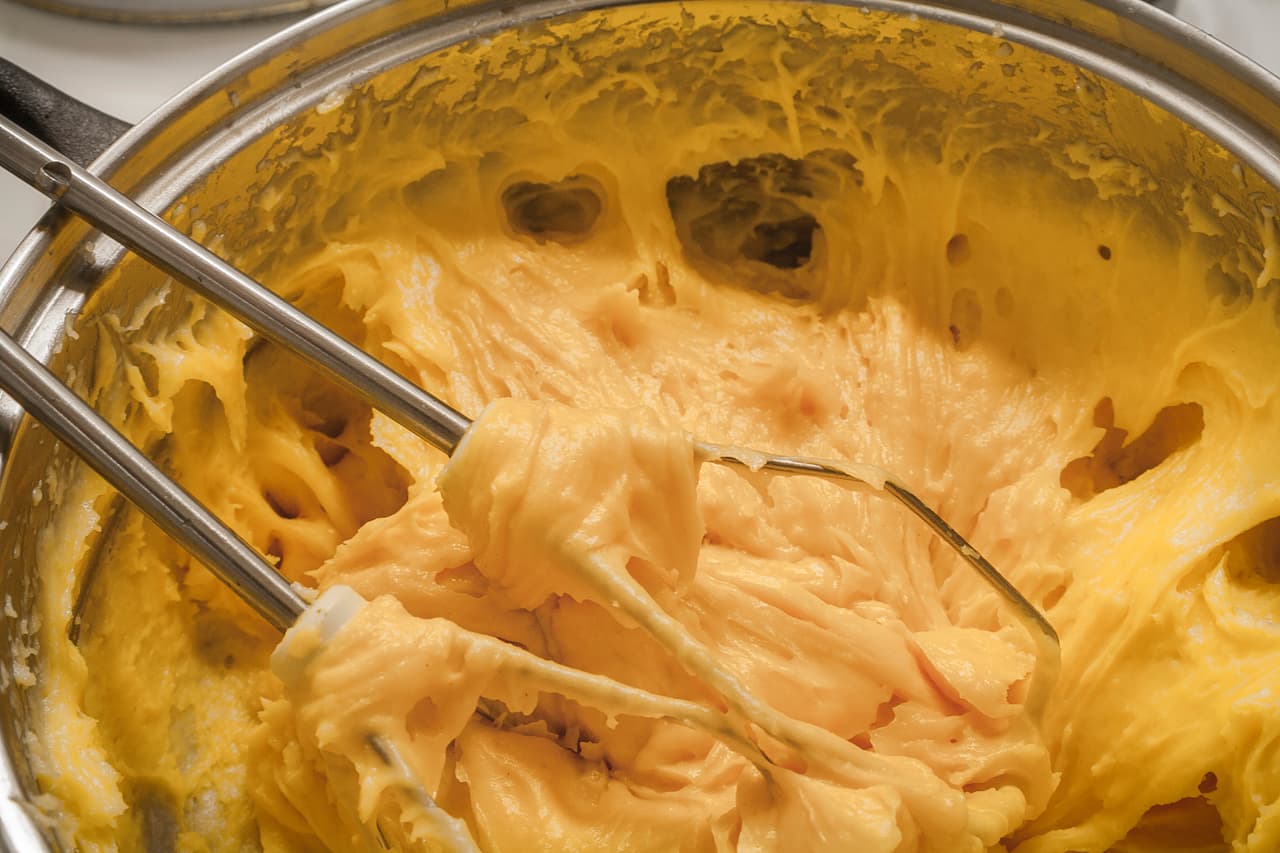 Tritura las pieles en la batidora o licuadora y añade tres cucharadas de zumo y las almendras; mezcla todo muy bien. En una cacerola aparte forma un almíbar con el azúcar y el resto del zumo. Después añade la mezcla previa y deja cocer todo por diez minutos.