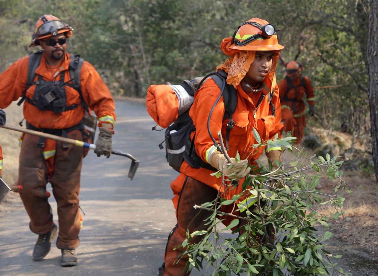Prisoners from the McCain inmate crew from San Diego, Calif., clear brush from a road on Wednesday, Oct. 11, 2017 in Calistoga, Calif. The wildfires tearing through California wine country flared anew Wednesday, growing in size and number as authorities issued new evacuation orders and announced that hundreds more homes and businesses had been lost. (AP Photo/Ben Margot)