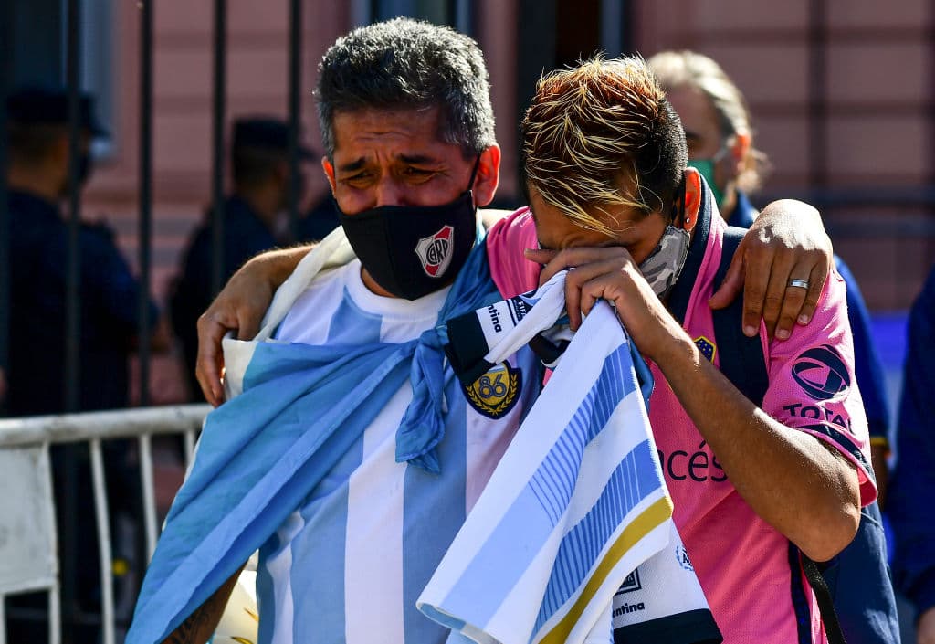 Un par de fanáticos, uno del club River Plate y otro de su rival, Boca Juniors, se consuelan al salir de la Casa Rosada donde permanece el cuerpo de Maradona. El astro falleció el mismo día que Fidel Castro, e 25 de noviembre.