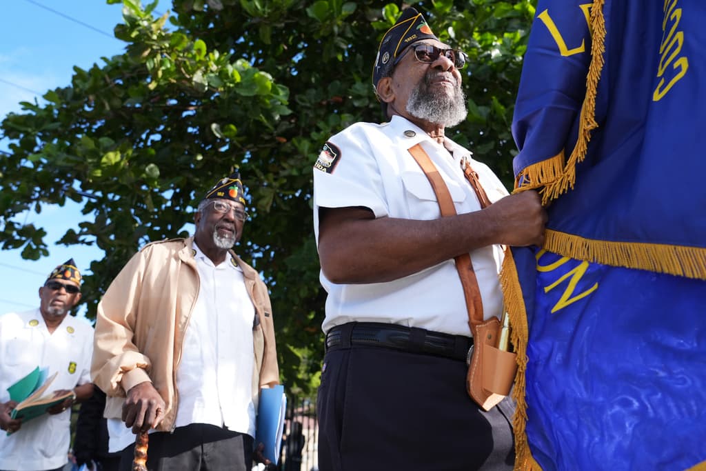 El veterano Richard Curry, del puesto 182 de la Legión Americana, porta una bandera durante una ceremonia del Día de los Veteranos.