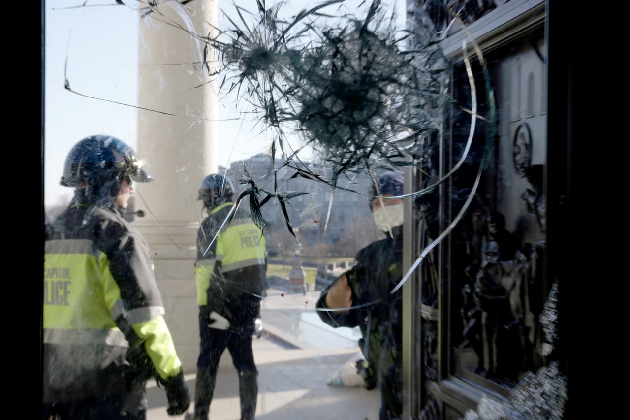 Oficiales de la policía del Capitolio inspeccionan los daños a una de las puertas por donde entró la turba que asaltó al Congreso. El incidente ocurrió durante la sesión que formalizó los resultados del 
<a href="https://www.univision.com/noticias/elecciones-en-eeuu-2020/colegio-electoral-vota-por-biden-y-es-oficialmente-presidente-eeuu">Colegio Electoral que dieron la victoria a Joe Biden</a>. 
<a href="https://www.univision.com/noticias/politica/en-fotos-partidarios-de-trump-entran-a-la-fuerza-al-capitolio-de-estados-unidos-protesta-donald-trump-joe-biden-elecciones-2021-fotos?utm_campaign=Univision%20Noticias&utm_medium=social&utm_source=facebook&fbclid=IwAR3pvyQJws7bUoRLnfLROfjKB1-4SjK7yTuIfuFzqdlQKZmi8gl5v9ud4Lg"><u>Vea aquí las fotografías del asalto al Capitolio en medio de la sesión para confirmar triunfo de Biden</u></a>