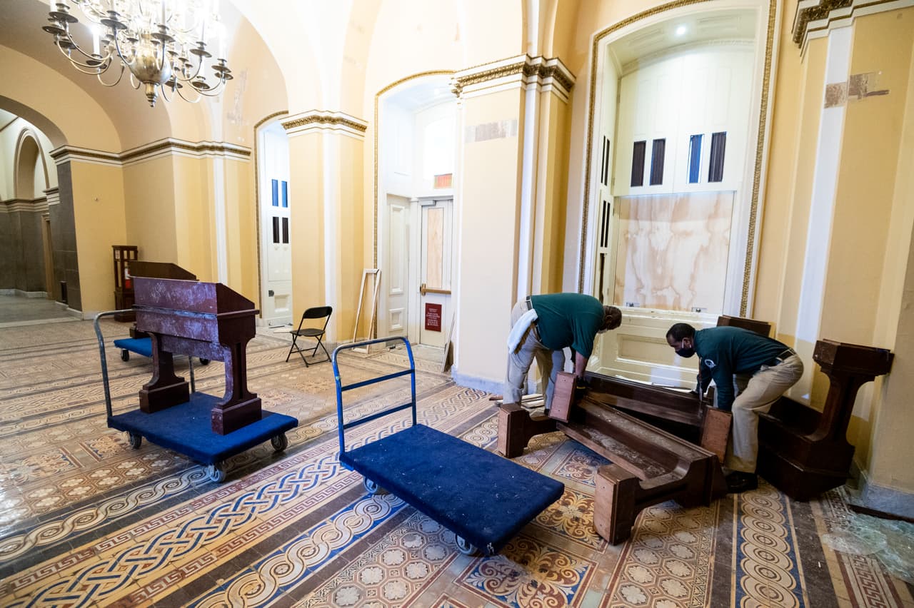 Los empleados del Congreso recogiendo el mobiliario dañado al día siguiente del incidente.